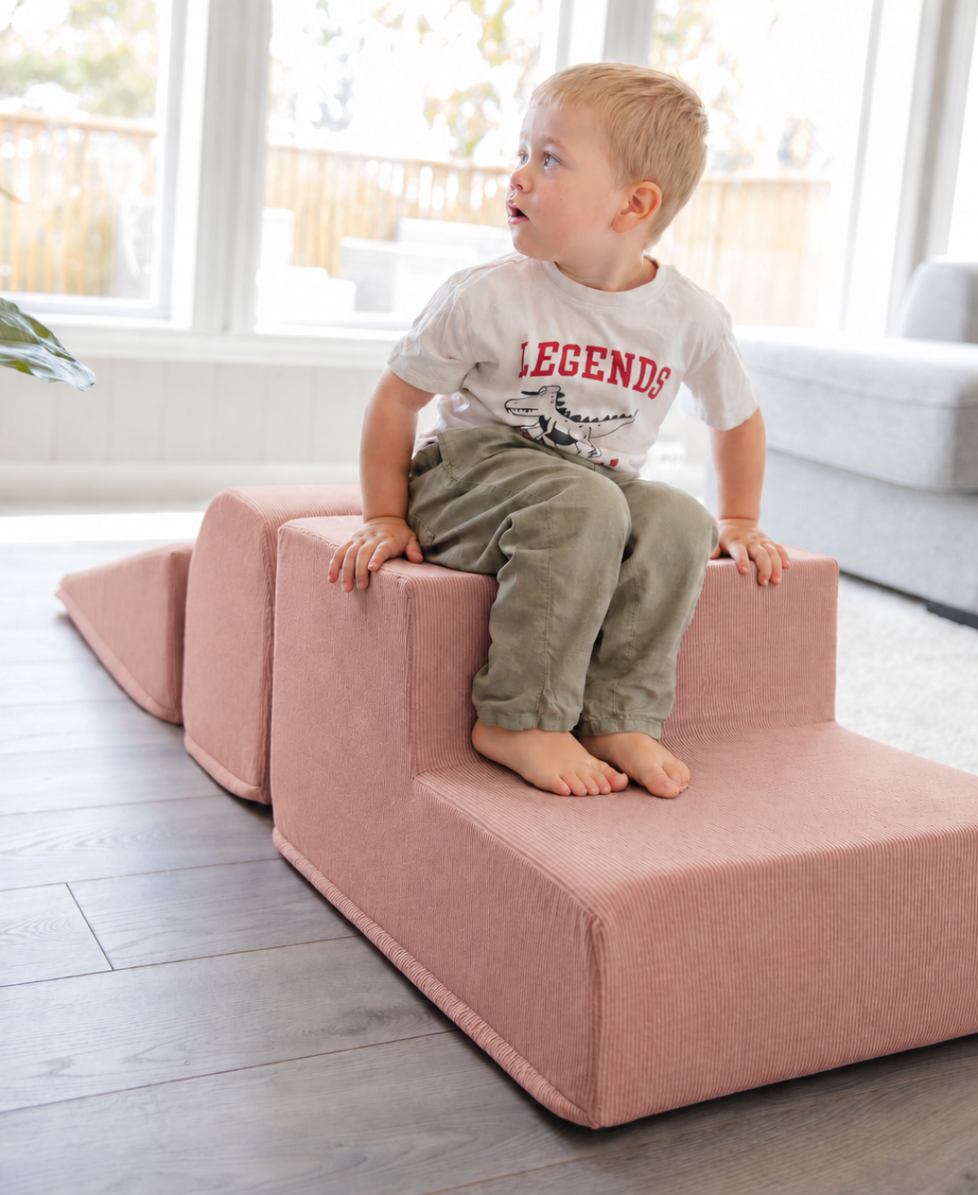 Liten gutt i hvit T-skjorte sitter på Trollefant Skumblokker 3 Deler i rosa cord, satt opp som trapp i lys stue