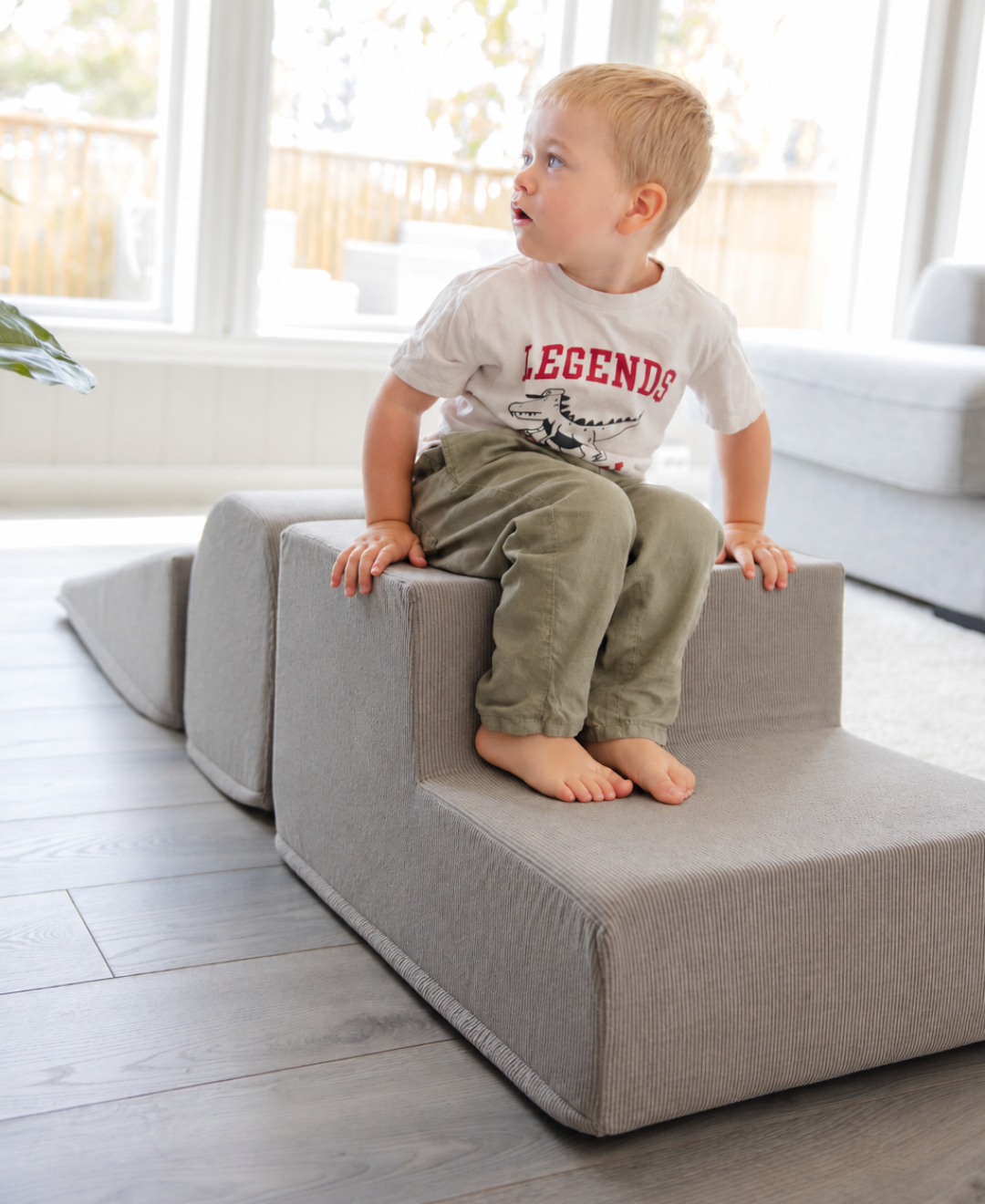 Liten gutt i hvit t-skjorte sitter på Trollefant Skumblokker 3 deler i grå cord i lyst stuemiljø